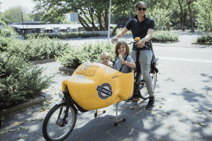 A father on a clog bike with a baby and a girl